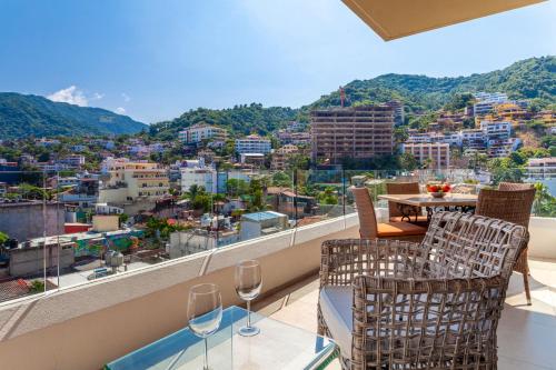 a balcony with wine glasses and a view of a city at Zenith 601, Zona Romantica, 2 Balconies with Incredible Views, Rooftop Pool in Puerto Vallarta