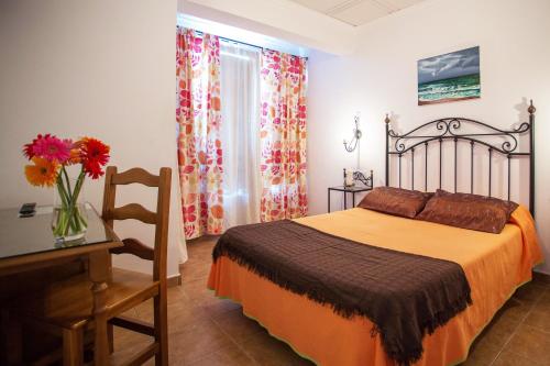 1 dormitorio con 1 cama, 1 mesa y 1 jarrón de flores en Hotel Nuro en Barbate