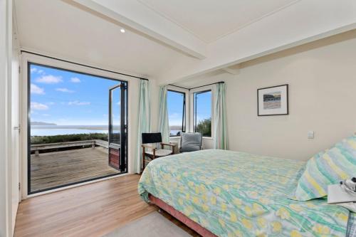 a bedroom with a bed and a large window at Taste Of Paradise with WiFi!- Mangawhai Heads Home in Mangawhai
