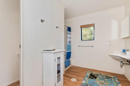 a white bathroom with a sink and a fireplace at Taste Of Paradise with WiFi!- Mangawhai Heads Home in Mangawhai