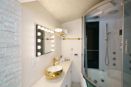 a white bathroom with a sink and a shower at Kakureyado Fujikawaguchiko in Fujikawaguchiko