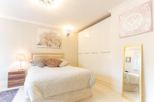 a white bedroom with a bed and a mirror at Modern apartment close to central London (zone 2) in London