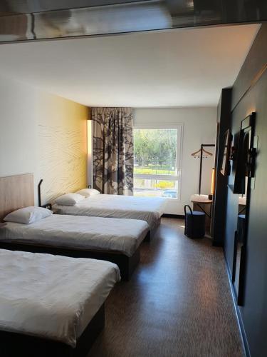 una camera d'albergo con tre letti e una finestra di B&B HOTEL Ouistreham a Ouistreham