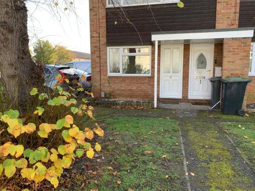 a house with a white door and a tree at Saint Johns Rest in Biggleswade