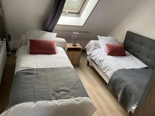 deux lits dans une chambre avec une fenêtre dans l'établissement Coeur de Solrézis, à Solre-le-Château