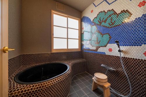 uma casa de banho com uma banheira e uma parede em mosaico em Osaka Sakainoma hotel Hama em Sakai