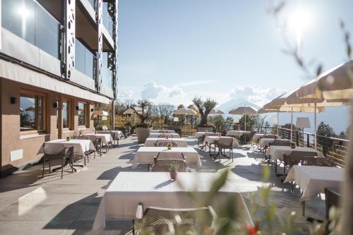 a row of tables and chairs on a patio at Oliven- & Genusshotel Hirzer in Schenna