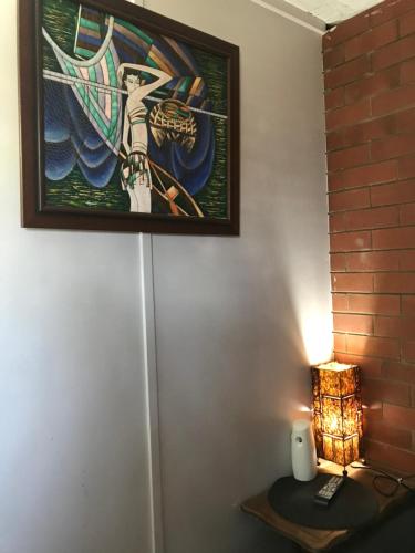 a table with a lamp and a picture on the wall at XYL Holiday Inn in Caloundra