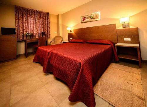 a hotel room with a bed with a red blanket at Hotel Ciutat de Carlet in Carlet