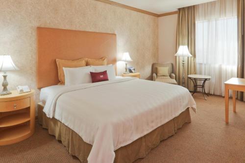 Cette chambre comprend un grand lit et une chaise. dans l'établissement Crowne Plaza Torreon, an IHG Hotel, à Torreón