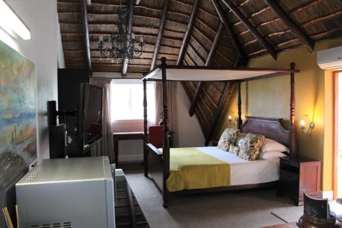 1 dormitorio con cama con dosel en una habitación en Windfall Plett, en Plettenberg Bay