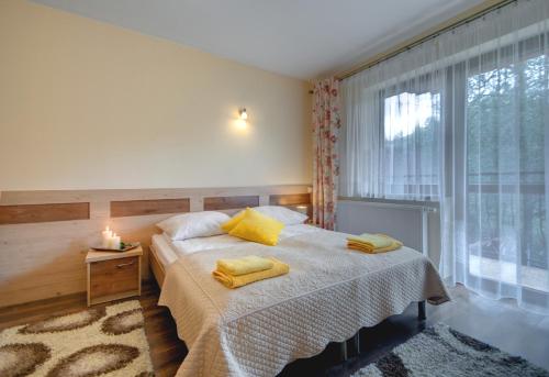 a bedroom with a bed with yellow pillows and a window at Willa u Łapów in Kościelisko