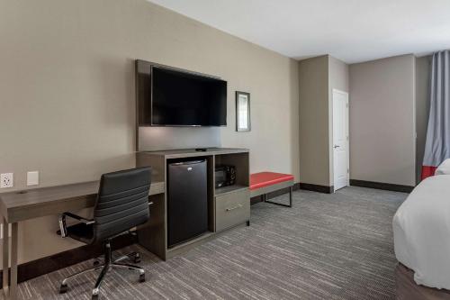 a hotel room with a bed and a desk with a television at Comfort Inn & Suites in Olive Branch
