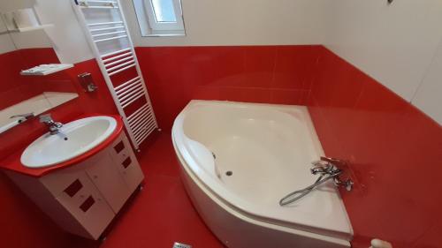 a red bathroom with a white tub and a sink at Pensiunea Lucy in Sinaia