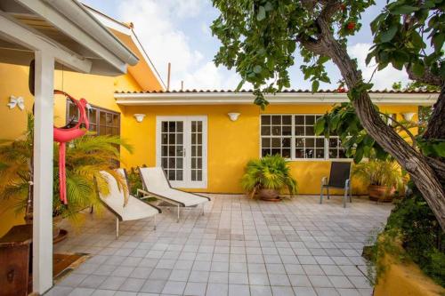 a yellow house with a patio with chairs and plants at Villa Seaside Boca Sami in Sint Michiel