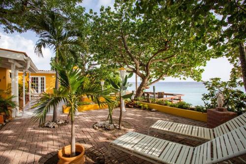 a patio with benches and trees and the ocean at Villa Seaside Boca Sami in Sint Michiel