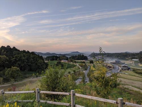 a view from a hill with a fence and a road at Guesthouse Hajimari in Kashihara