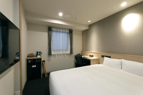 a hotel room with a large bed and a desk at At Inn Hotel Toyotashi Eki in Toyota