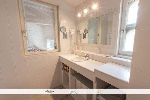 a white bathroom with a sink and a mirror at LA GRANGE DE BELLEFONTAINE et sa piscine privée in Bellefond