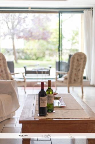 two bottles of wine sitting on top of a wooden table at LA GRANGE DE BELLEFONTAINE et sa piscine privée in Bellefond