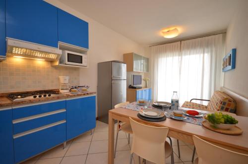 a kitchen with blue cabinets and a table with chairs at Villaggio Planetarium Resort in Bibione