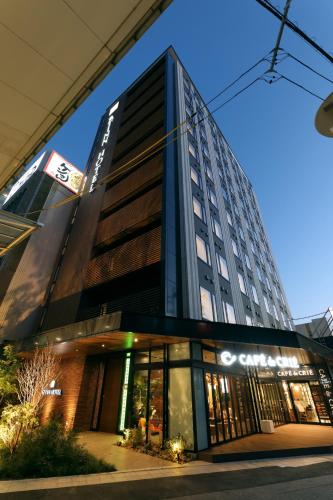 a tall building with a store in front of it at At Inn Hotel Toyotashi Eki in Toyota