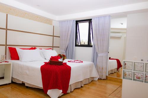 1 dormitorio con 1 cama grande con manta roja en Granlago Hotel, en Pouso Alegre