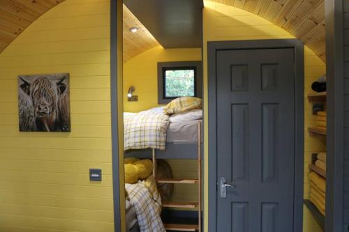 Kleines Zimmer mit 2 Etagenbetten und einer Tür in der Unterkunft Glampods Glamping Pod - meet Highland Cows and Sheep Elgin in Elgin