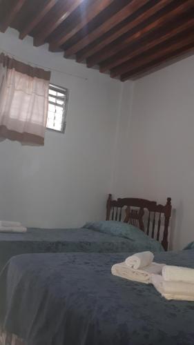 a bedroom with a bed with blue sheets and a window at Hostal Villa Brisa in Ballenita