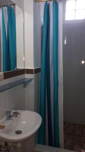 a bathroom with a sink and a blue shower curtain at Hostal Villa Brisa in Ballenita
