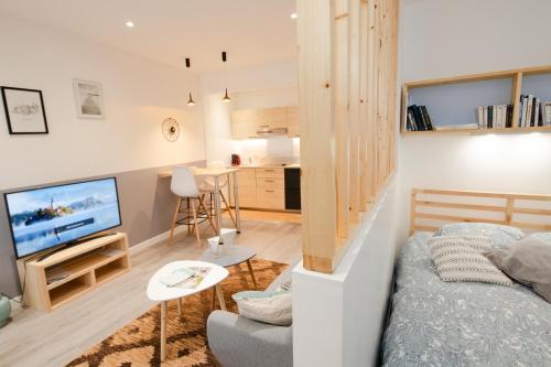ein Wohnzimmer mit einem Bett, einem TV und einem Tisch in der Unterkunft Roudadoux in Issoire