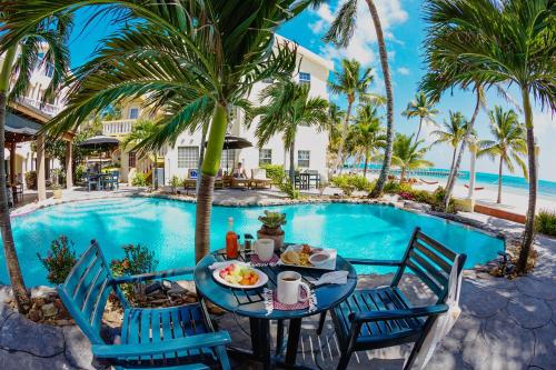 a table with a plate of food next to a swimming pool at Pelican Reef Villas Resort in San Pedro