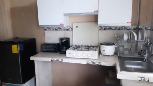 a small kitchen with a stove and a sink at Suite frente a la playa in Playas