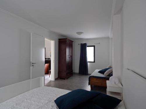 1 dormitorio blanco con 1 cama y 1 habitación con ventana en Joaninha's Beach House, en Glória