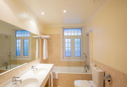 a bathroom with a sink and a tub and a toilet at Veneza Hotel in Aveiro