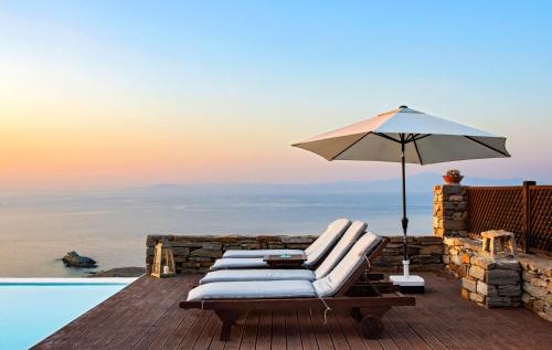 a group of lounge chairs with an umbrella on a deck at Villa Aqua Marina in Vourkarion