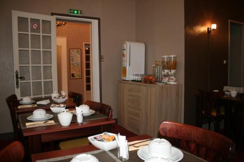 un comedor con una mesa con platos. en Cit'Hotel Hôtel Beauséjour, en Cherbourg-en-Cotentin
