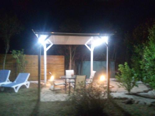 a gazebo with a table and chairs at night at Gîte climatisé L'OISELLERIE in Castelnou