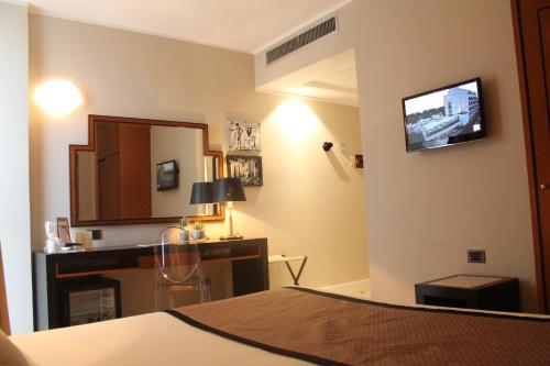 a bedroom with a bed and a desk and a television at Mec Paestum Hotel in Paestum