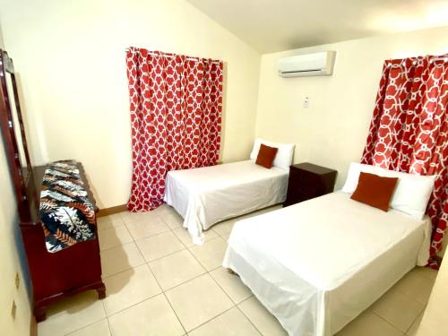 a hotel room with two beds and red curtains at The Intimate Paradise Close to 876 Beach in Falmouth