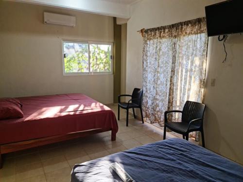 1 Schlafzimmer mit 2 Betten, 2 Stühlen und einem Fenster in der Unterkunft Posada Playa Linda in Ixtapa