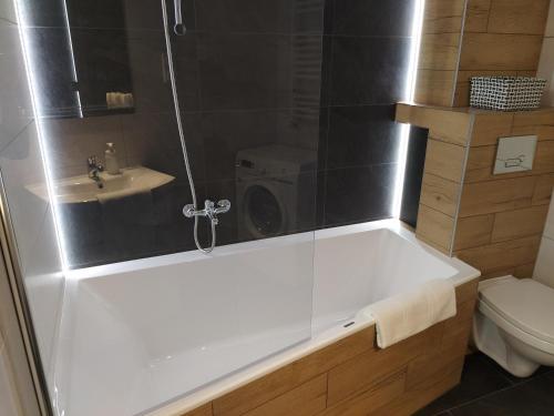 a bathroom with a bath tub and a washing machine at Apartament 36 in Nowy Targ