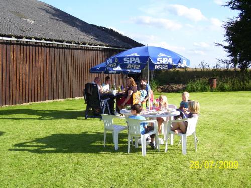un gruppo di persone sedute a un tavolo sotto un ombrello di Ferienhaus Neuville in ruhiger Lage a Bullange/Büllingen