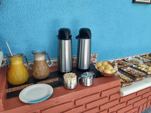 a counter with two thermos and a tray of food at POUSADA CARVALHO in Pirenópolis