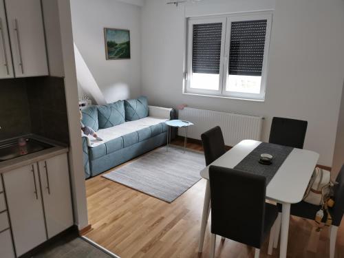 een woonkamer met een blauwe bank en een tafel bij Apartman Divcigora Sokic in Divčibare