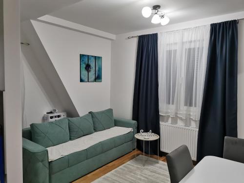 ein Wohnzimmer mit grüner Couch und blauen Vorhängen in der Unterkunft Apartman Divcigora Sokic in Divčibare