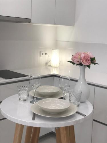 a table with plates and glasses and a vase with flowers at Viana é CORAÇÃO DE OURO in Viana do Castelo