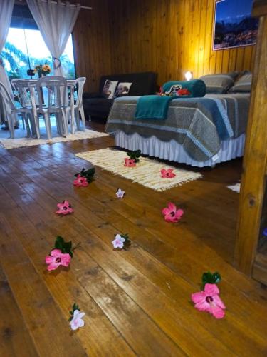 a room with a bed and pink flowers on the floor at Pousada Chalé Suiço Bombinhas in Bombinhas