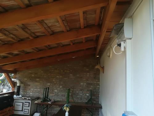 a room with a stone wall and wooden ceiling at Vár-Liget Vendégház in Kisnána