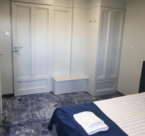 a bedroom with white cabinets and a bed with blue sheets at Pensjonat Retro in Łomża